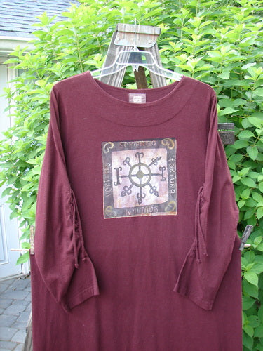 1999 Starlight Dress in Deep Burgundy, featuring a Celtic Compass theme. Made from organic cotton, this dress has a double-layered neckline, lovely sleeve lacings, and a longer shape. The dress is accented with a vertical drawcord and continuous paint. Perfect condition. Size 2.