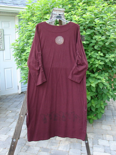 Image alt text: "1999 Starlight Dress in Deep Burgundy, featuring a double-layered neckline, sleeve lacings, and a longer, straighter shape. Celtic compass theme paint accents and vertical drawcord hem. Made from organic cotton. Size 2."