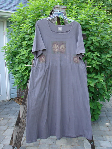 1999 Windmill Dress Butterfly Raven Size 2: A dress on a clothes rack with a butterfly design. Flattering A-lined shape, double-paneled neckline, yoked waist, curved bodice, flared hemline, and deep side pockets. Organic cotton.