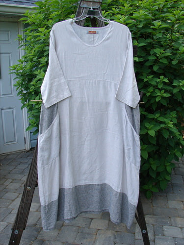 Image alt text: Barclay Linen Stripe Tulip Dress on clothes line, featuring scoop neckline, oversized pockets, and tulip bottom flare.