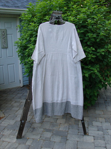 Image: A white dress on a clothesline with a sign on a door in the background.

Alt text: Barclay Linen Stripe Tulip Dress hanging on a clothesline with a sign in the background.