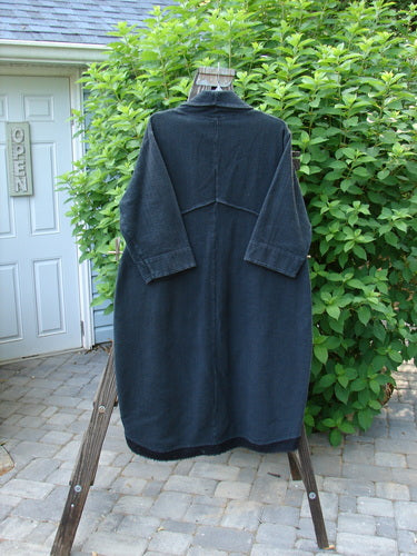 A Barclay Thatch Big Collar Coat in Deep Forest, size 1, hangs on a clothes rack. Densely knit, textured fabric with exterior stitchery, drop front pockets, and V-stitched back seams. Cuffed sleeves, banded hemline, and four-button closure.