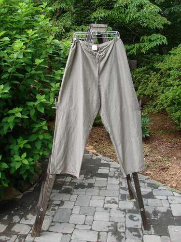 2000 Shaunting Silk Slant Drawcord Pant Cement Size 2: A pair of pants on a rack, featuring a rear elastic waistband with a drawcord front. Wider hips and lowers, with a slightly longer and lovely fall. Lengthier inseam and full length measurement.
