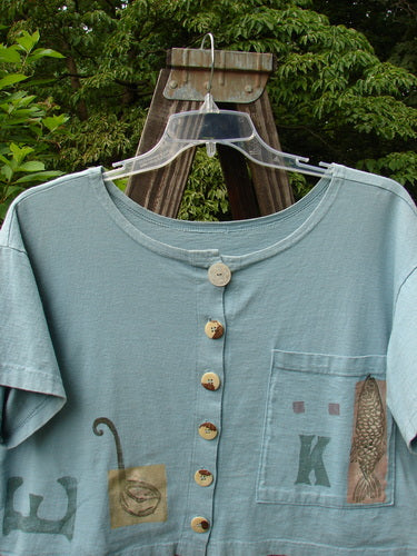 1994 Song Top Multi Letter "K" Ice Size 1: A wide, boxy shirt with a shallow neckline. Vintage buttons and a painted breast pocket add flair.