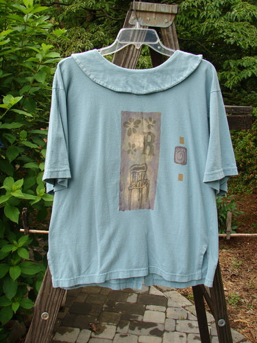 A 1994 Compass Top Chair Dusk Size 1: a blue shirt with a picture of a chair theme paint.