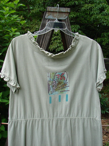 Image alt text: 1991 Short Milkmaid Dress in Sage, featuring a laced neck hem and sleeve line, with a unique center bell shape. Blue Fish patch sewn into the back neckline. Versatile waist for different looks. Bust 44, Waist 46, Hips 48. Length 37 inches.