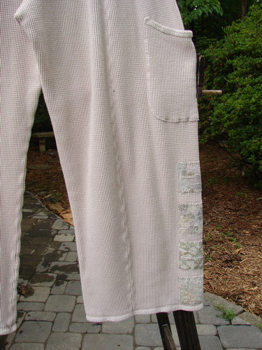 A close-up of a white Barclay Thermal Patched Pottery Pant with painted garden patches. Features include elastic waist, generous hip measurements, and deeper drop exterior pockets. Size 1.