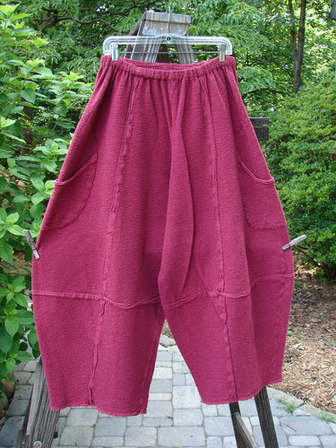 Barclay Crepe Sectional Pocket 4 Square Pant in Cranberry. Unique bottom cut creates a 3D diamond shape from knee down. Exterior wrap around hip pockets, elastic waistband, and textured fabric. Size 1.