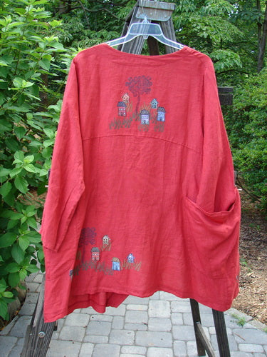 A red Barclay Cross Dye Linen Tidal Jacket with a drawing of a little village theme paint. Features include a deeper neckline, double wrap side exterior pockets, and a varying front hemline. Perfect condition. Size 2.