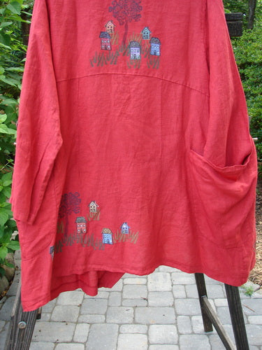 A red Barclay Cross Dye Linen Tidal Jacket with a village theme paint design. Features include a deeper neckline, two-button cross-over side closure, varying front hemline, and double wrap side exterior pockets. Size 2.