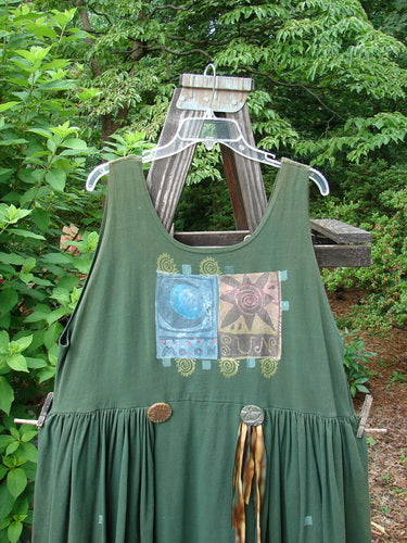 The 1992 Peplum Dress Sun Moon Star Evergreen OSFA features a scooped neckline, oversized vintage buttons, and a gathered peplum design, highlighted by hand-dyed silk ribbon accents.