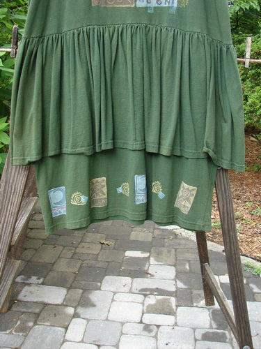 1992 Peplum Dress Sun Moon Star Evergreen OSFA displayed on a rack, showcasing its oversized vintage buttons, gathered peplum, and hand-dyed silk ribbon accents, epitomizing Bluefishfinder.com's vintage style.
