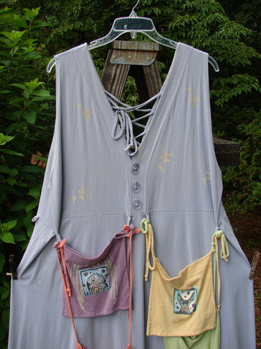 Image alt text: 1997 Salt Water Taffy Jumper Rain Size 2: A pair of dresses on a wooden pole, with a yellow bag and a pink bag with pictures on them.