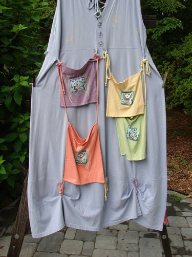 1997 Salt Water Taffy Jumper Rain Size 2: A dress with bags on a clothesline, close-up of a dress, pink and purple shirt on a surface, yellow and green apron on a hook, close-up of a bag.