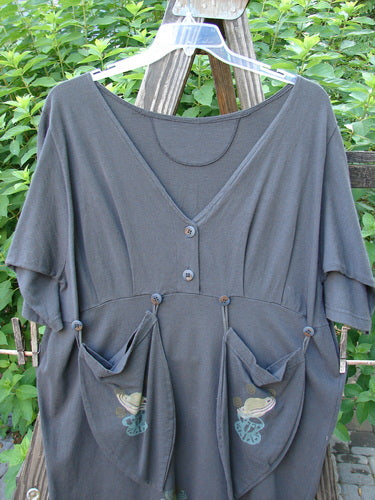 1994 Muse Dress Celestial Planet Blue Coal Size 1: A grey shirt with pockets on a wooden fence. Deep V neckline, tear drop pockets with buttons, empire waist seam, 3/4 inch sleeves.