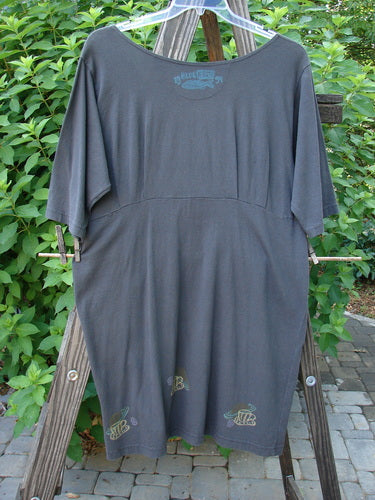 A 1994 Muse Dress in Blue Coal, size 1, on a clothes rack. Deep V neckline, tear drop pockets with buttons, empire waist seam, and celestial theme paint.