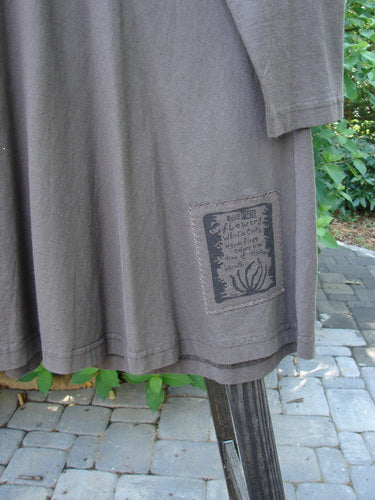 1994 Poppy Dress Collarless Figure Eight Woman Humus Size 2: Long-sleeved shirt on a pole, close-up of a grey shirt, close-up of a sign and metal post, green leaf on a stone surface.
