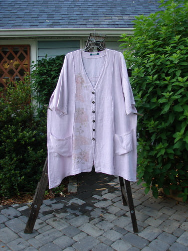 Image alt text: Barclay Linen Double Tie Back Jacket Wind Branch Pink Cloud Size 2 - A long white shirt with buttons on a rack, close-up of a towel from a rack, white towel from a clothesline, close-up of a fence, close-up of a bush, close-up of a roof, stone pavement with a white cloth on it.