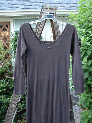1992 Cotton Lycra Back Vent Dress Unpainted Black Olive Size 2: A long-sleeved dress on a wooden pole, featuring a tiny hourglass shape, rear kick vent, and pegged hemline. Perfect for layering.