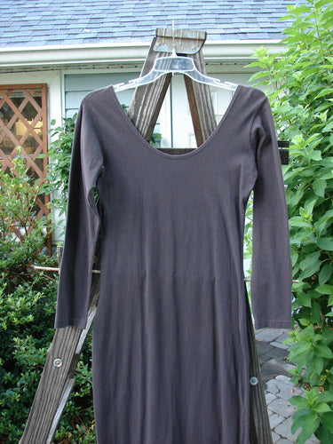 A Cotton Lycra Back Vent Dress in Black Sand on a wooden rack. Hourglass shape, rear kick vent, V front and deeper rear neckline. Size 2.