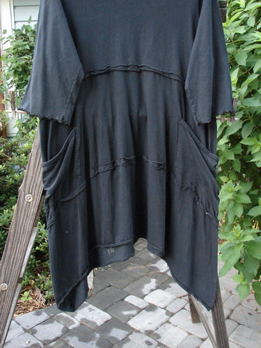 A black tunic dress with double pockets and a leaf garden theme paint design. Three-quarter length sleeves and a varying hemline.