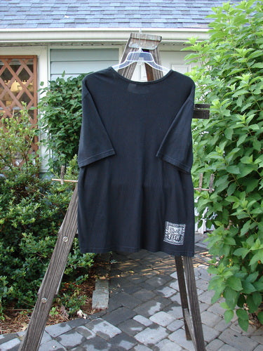 A black short-sleeved tee with a flattened neckline and Tea for Two theme paint. Made from organic cotton. Size 0.