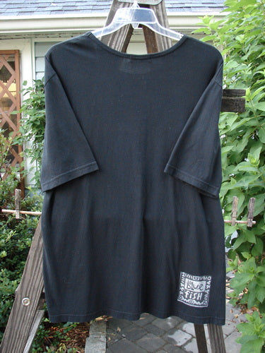 A black t-shirt with a flattened neckline and a Tea for Two theme paint design. Made from organic cotton. Size 0.