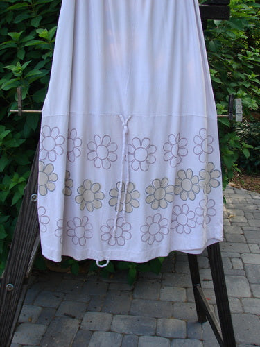 A Barclay Spring Shade Skirt in Pale Pink, featuring a floral pattern on a white background. Made from Organic Cotton, this skirt has a full elastic waistband, a varying hemline, and a long rippie cord for adjustable styling. Perfect for a summer collection.