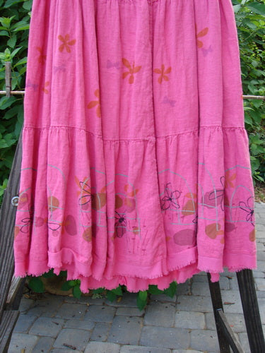 Barclay Linen Drawstring Ruffle Skirt Daisy Fence Flamingo Size 2: A pink dress with flowers on a rack, featuring a full drawstring waistline, alternating horizontal seams, and a slight billowy flare with sweet fringe edges. Perfect for building a special look with a sweet daisy theme. Length: 37".