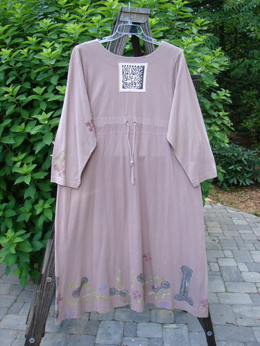1993 Modernismo Duster Dress Columns Ash Pink OSFA: A vintage dress with a leaf theme paint design, wooden buttons, kangaroo pockets, and a scooped neckline. It has a sweeping lower and a drawcord back.