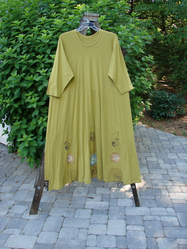 1998 Mystic Dress Celestial Terra Vert Size 2: A green dress with a pattern, bubble hemline, and rope cord tie. 3/4 length sleeves and abstract pinwheel theme paint.