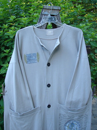 1999 Interlock Long Square Cardigan Jacket Fern Pod Ash Size 0: A grey jacket with a patch on it, featuring a hook and plastic objects.