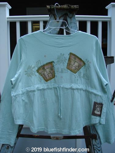 1999 Coffee Top Flowerpot Mint Size 1: A light blue shirt with a flower pot design. Ceramic button closures and a sweeping rounded hemline.