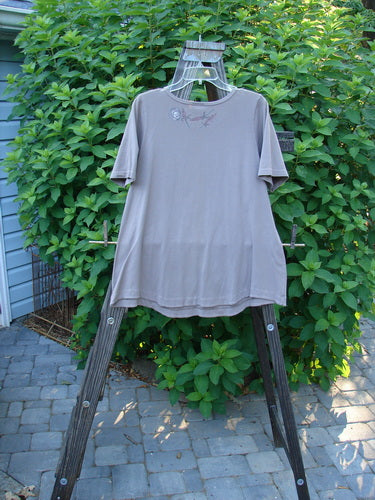 A Barclay Cotton Lycra Short Sleeved Twinkle Top in Grey Mauve, displayed on a wooden clothes rack.