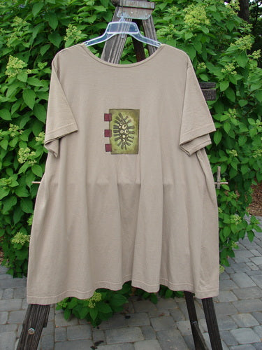 Image alt text: "1997 Montage Dress Triple Leaf Wheat Size 2: A tan shirt with a square design, two oversized colorful pockets, and top center button closures."