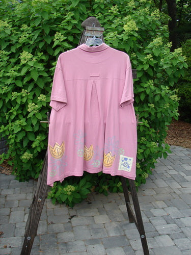 1999 Tarragon Top Tulip Daisy Raspberry Size 2: A pink shirt on a wooden stand, featuring a deep vented sides, pleated and gathered back, and a varying hemline.