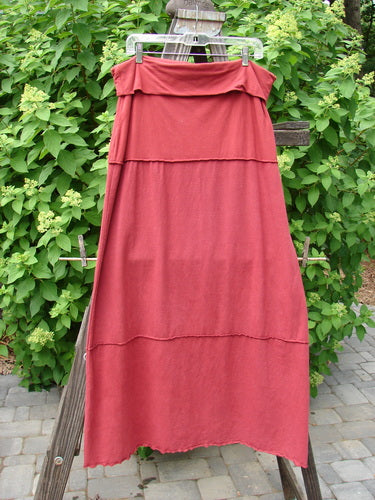 Barclay Hemp Cotton Decora Fold Over Skirt Unpainted Brick Size 2: A red skirt on a clothes rack with a double paneled waistline, adjustable length, and decorative stitching.