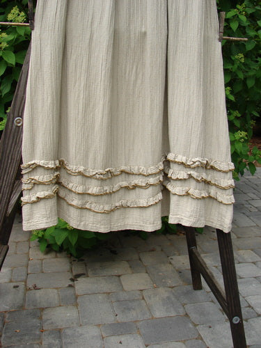 Barclay Rib Silk Triple Flutter A Line Skirt in Unpainted Sand. A white ruffled skirt on a rack, with a close-up of the skirt's fluttery bottom and silken texture.