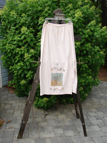 Image: A pair of pants on a rack. A white towel on a clothes rack. A white cloth with a design on it. A white towel from a ladder. A wooden post with a screw in it. A white pants on a rack.

Alt text: 1994 Panel Skirt Daisy Lane Tea Dye Size 2: Full rear elastic waistline, front skinny painted panel with curved side buttons and daisy flower. Medium weight cotton jersey. Length: 38 inches.