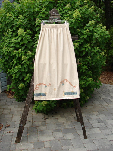 1995 Kick Skirt Resort Travel Champagne Size 2: A skirt on a rack with a full elastic waist, widening shape, and sassy rear kick pleat. Front painted upward scooped hemline and sweet painted accents on the waistband.