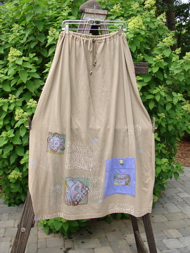 Barclay Big Pocket Skirt: A beige skirt with a patch, drawstring waistline, bell-shaped bottom, and giant exterior pocket. Features two deep side pockets and Lets Shop Now theme paint.
