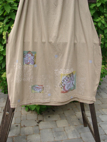 Barclay Big Pocket Skirt: A wheat-colored skirt with a drawstring waistline, bell-shaped bottom, and a super giant exterior pocket with a vintage blue fish button closure. Features two deep side pockets and lets shop now theme paint.