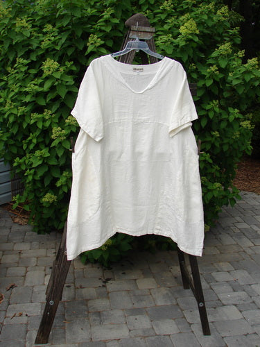 A white Barclay Linen Sailor Dress with a batiste adorned neckline, swaying lower hemline, and exterior drop front pockets. Size 2, unpainted.