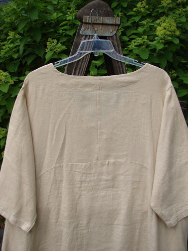 Image alt text: Barclay Linen Urchin Side Pocket Tunic Dress, size 2, on a wooden stand, with V-shaped neckline, drop pockets, varying hemline, and three-quarter length sleeves.