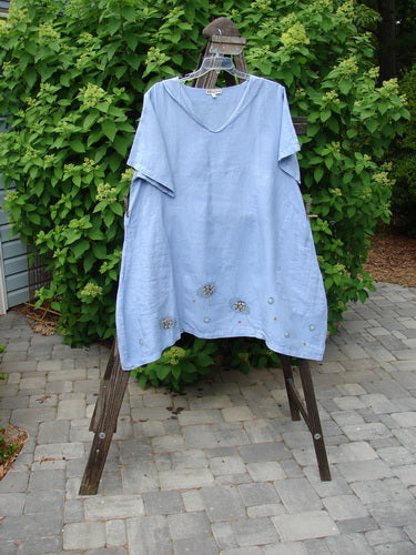 A Barclay Linen Sailor Dress in Celestial Blue Sky, size 2. Features include a batiste adorned neckline, swaying lower hemline, empire waist seam, wider sleeves, and drop front pockets. Made from medium weight linen.