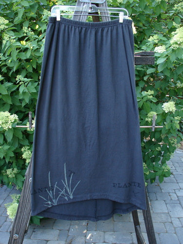 1998 Botanicals Corolla Skirt: A slenderizing, pocket-less black skirt with an elastic waistband. Upward scooped front hemline with a cloth accent in the botanical plant theme. Made from organic cotton. Size 2.