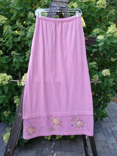 1999 Basket Skirt with Continuous Daisy theme, made from Raspberry Medium Weight Organic Cotton. A pink skirt on a clothesline with A-lined flair, elastic waistband, deep side pockets, and a specialized bottom. Size 0.
