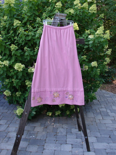 1999 Basket Skirt with Continuous Daisy theme. Raspberry colored skirt on a rack. A-line flair, elastic waistband, deep side pockets, and painted details. Size 0.