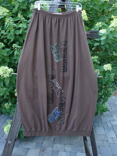 1996 Thermal Whimsical Skirt Tribal Molasses Size 2: A brown skirt with a design on it, featuring a gathered and ribbed hemline, sectional vertical panels, and abstract tribal theme paint.