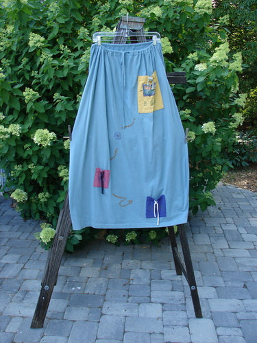 1996 Destination Skirt Travel by Path Sea Spray Size 2: A blue skirt on a wooden stand with a patch and painted pockets. Full drawstring waistline, widening lower bell shape. Terrific flare and tons of pockets.